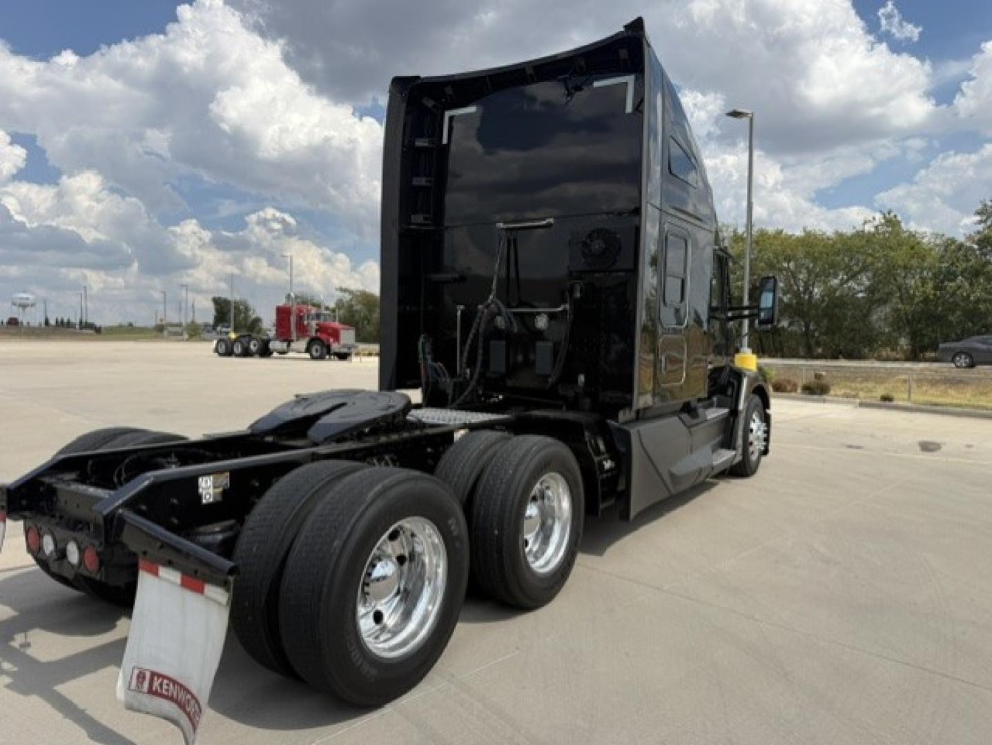 Kenworth T680 conventional sleeper tractor rear view with dual rear axles and black paint.