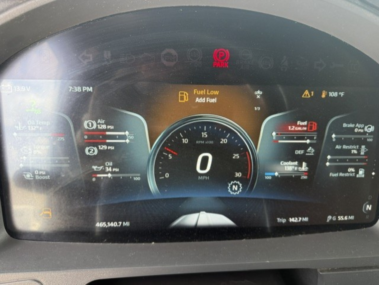 Kenworth T680 truck dashboard display showing speedometer at 0 mph, fuel gauge, temperature, and warning icons including Fuel Low, DEF, and coolant; multiple digital readouts and trip data visible.
