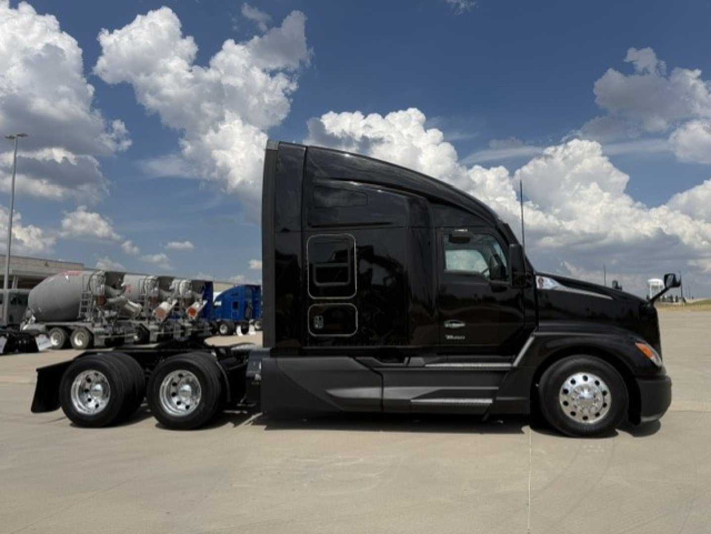 Kenworth T680 tractor in black paint with sleeper cab, side profile, three axles at rear, chrome fuel tanks and wheels.