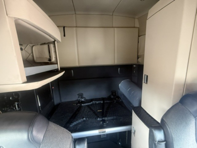Kenworth T680 cab interior with sleeper, storage cabinets, and bed area visible in forward view.