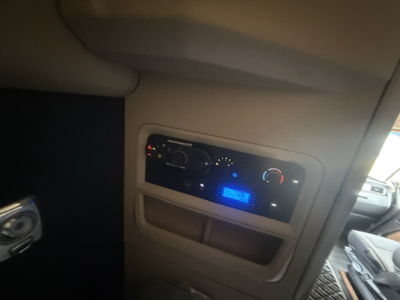 Dashboard area of a Kenworth truck cab with illuminated controls and digital display showing blue light.