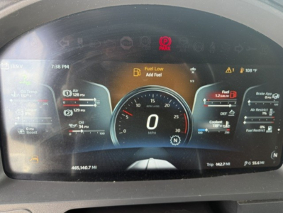 Kenworth T680 truck dashboard display showing speedometer at 0 mph, fuel gauge, temperature, and warning icons including Fuel Low, DEF, and coolant; multiple digital readouts and trip data visible.