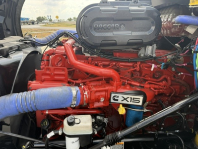 Kenworth T680 engine bay showing Cummins X15 badge and red engine components with blue hoses