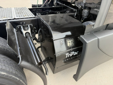 TriPac Evolution auxiliary power unit cabinet mounted on a Kenworth T680 chassis showing black box with TriPac Evolution logo.