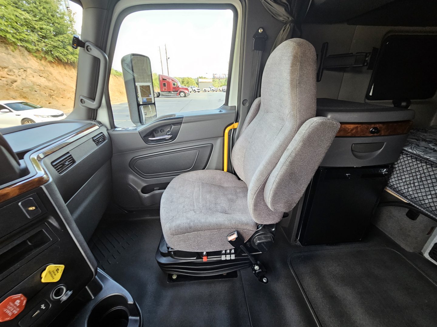 Truck cab interior showing driver seat and sleeper area with storage cabinet and dashboard elements.