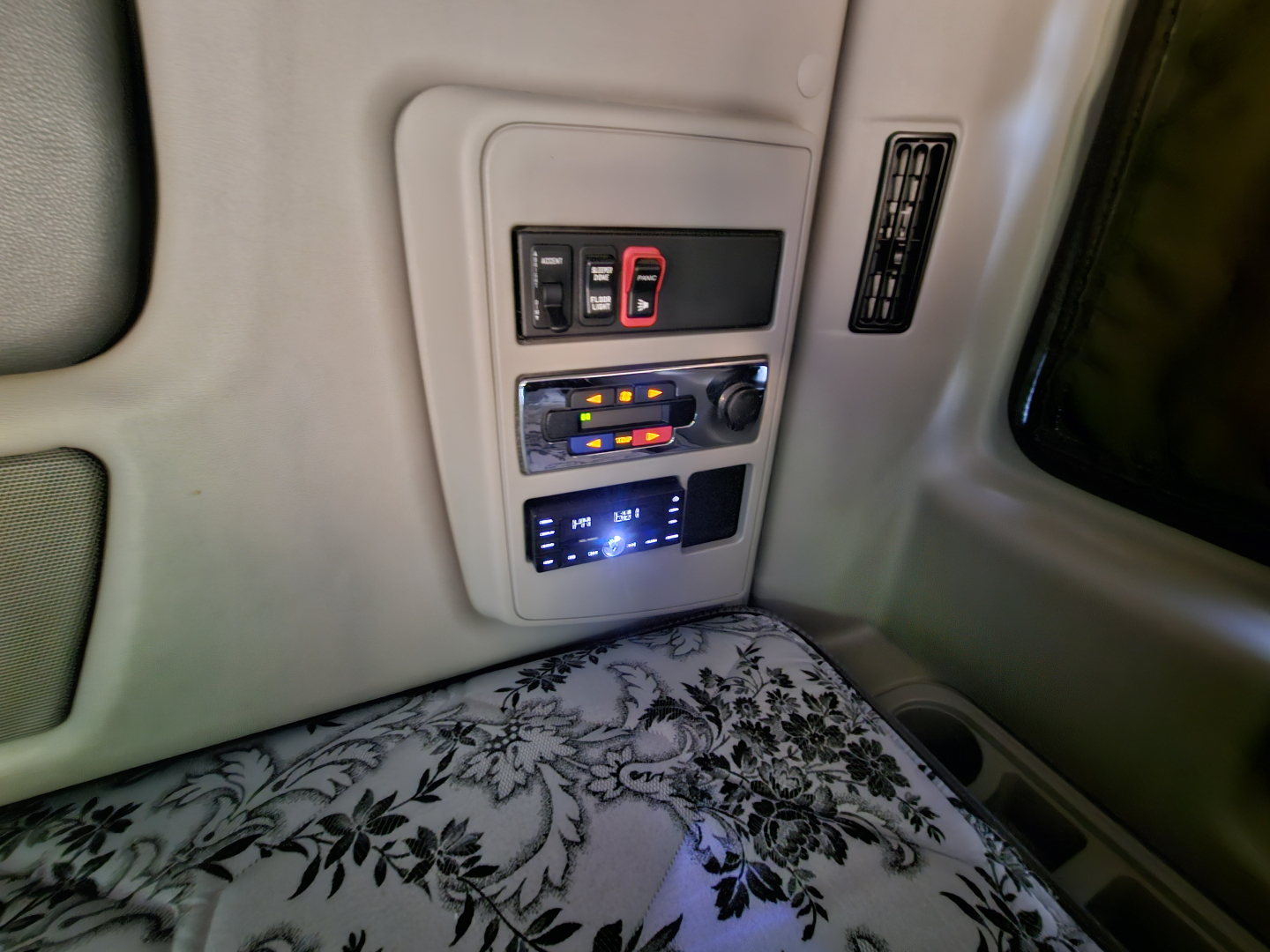 Interior overhead console of a sleeper cab showing switches and a blue digital display panel. Text on panels not fully legible.