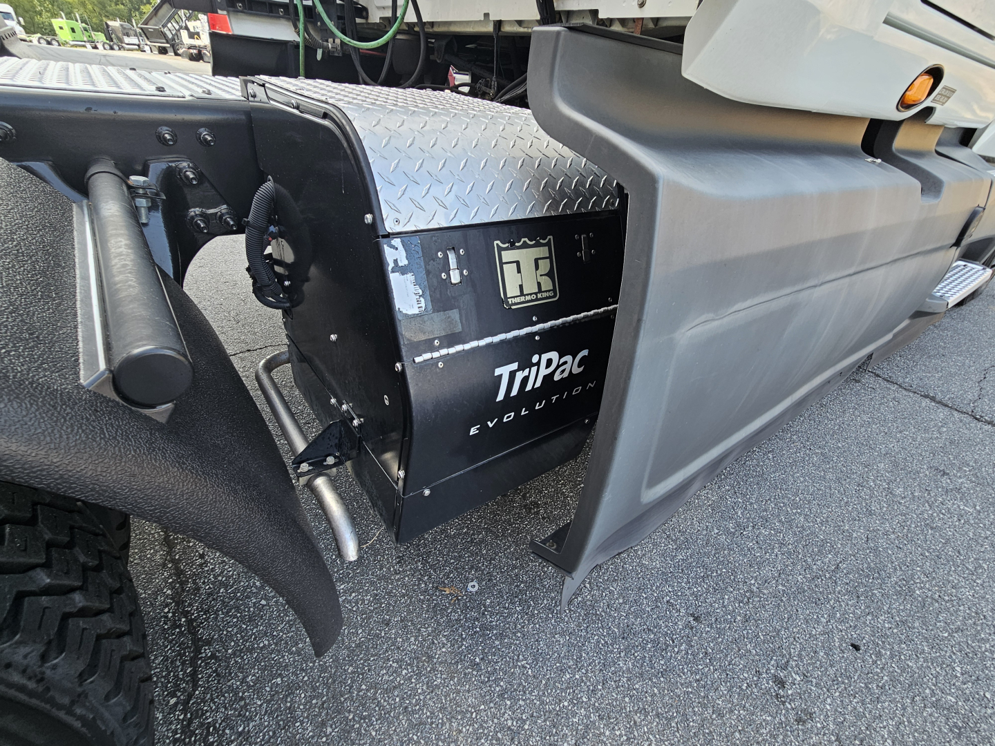 Truck component panel showing TriPac Evolution unit and diamond plate toolbox mounted between front wheel and cab on 2021 International LT625.