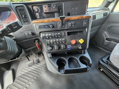 Truck cab interior view from left side showing dashboard with controls, cup holders, and storage compartments.
