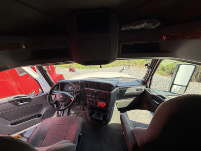 Interior of a 2021 International LT625 sleeper cab showing dashboard, steering wheel, and front seats; cabin view from passenger side; no visible text or labels.