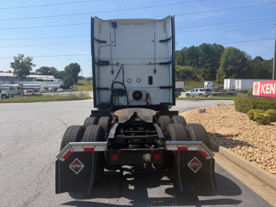 Rear view of a 2021 International LT625 tractor with dual rear axles and mudflaps displaying warning diamonds; back of cab shows white exterior, various hoses and connectors.