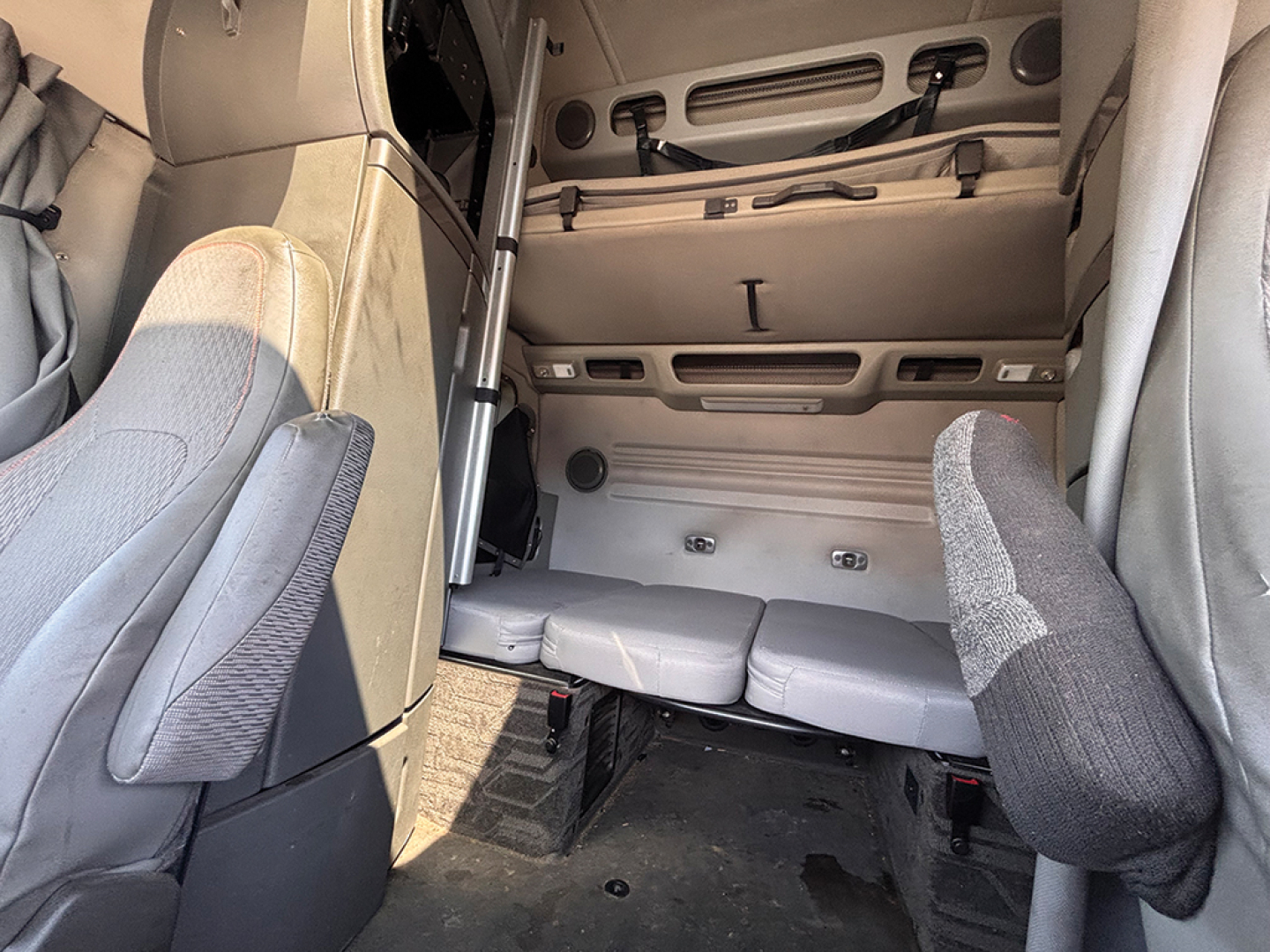 Truck cabin interior showing bunk area with seat backs and storage compartments.