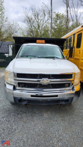 Chevrolet Silverado 3500HD dump truck front view showing grille, bumper, and cab with a roof beacon, adjacent to a yellow school bus.