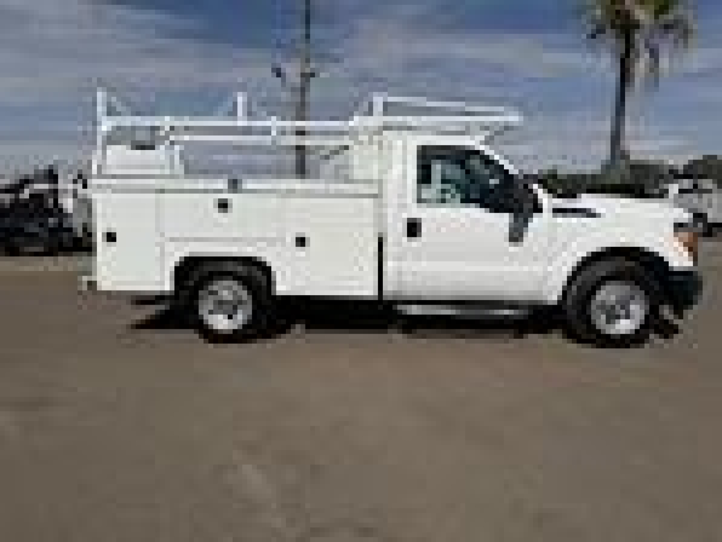 Ford F-250 utility truck side view with service compartments and ladder rack.