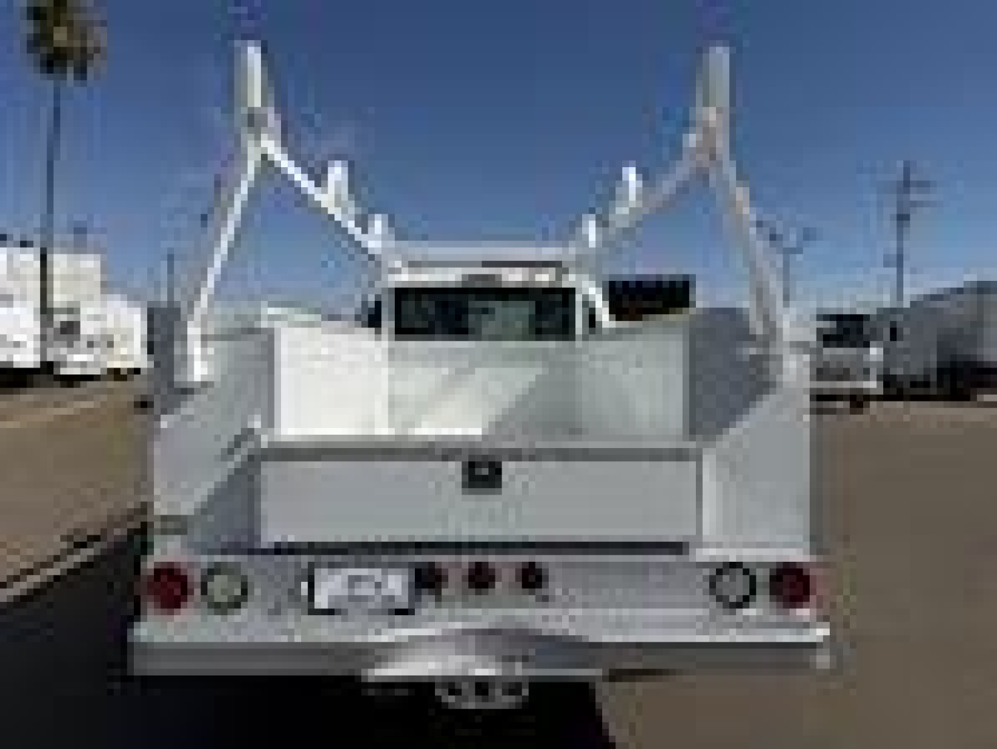 Flatbed service truck rear showing dual stake racks and rear lights.