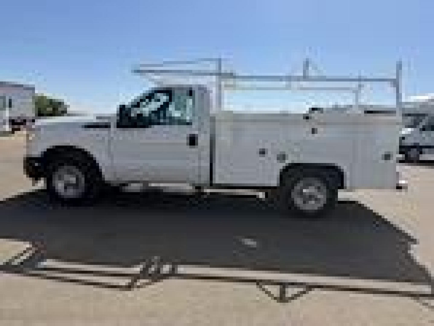 Ford F-250 utility service truck side view showing ladder rack and service body with compartments.