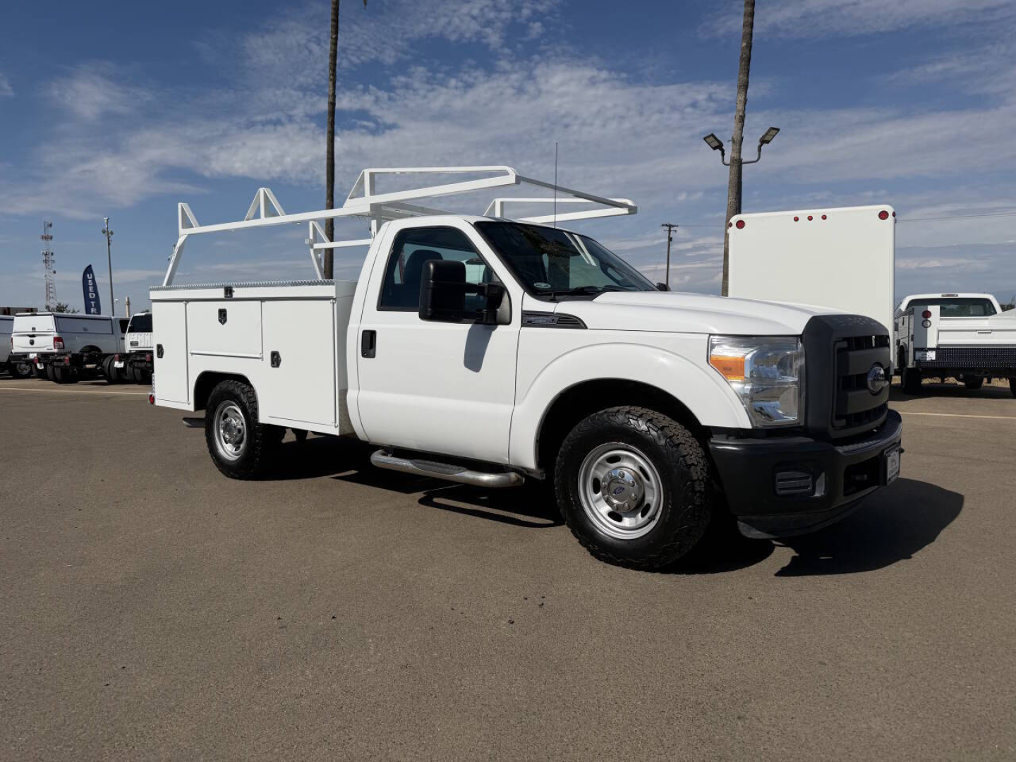 Service/Utility truck with ladder rack showing storage compartments and utility body, white Ford F-250 truck profile in a parking lot.