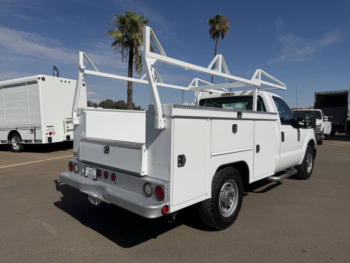 Ford F-250 utility/service truck rear and side view with large white aluminum service bed and ladder racks.