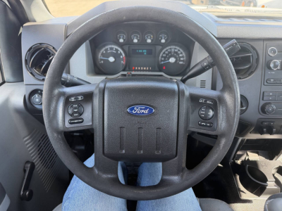 Dashboard and steering wheel of a 2015 Ford F-250 interior showing Ford emblem, instrument cluster, and steering wheel controls.