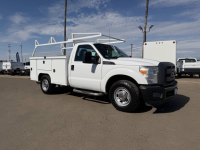Service/Utility truck with ladder rack showing storage compartments and utility body, white Ford F-250 truck profile in a parking lot.