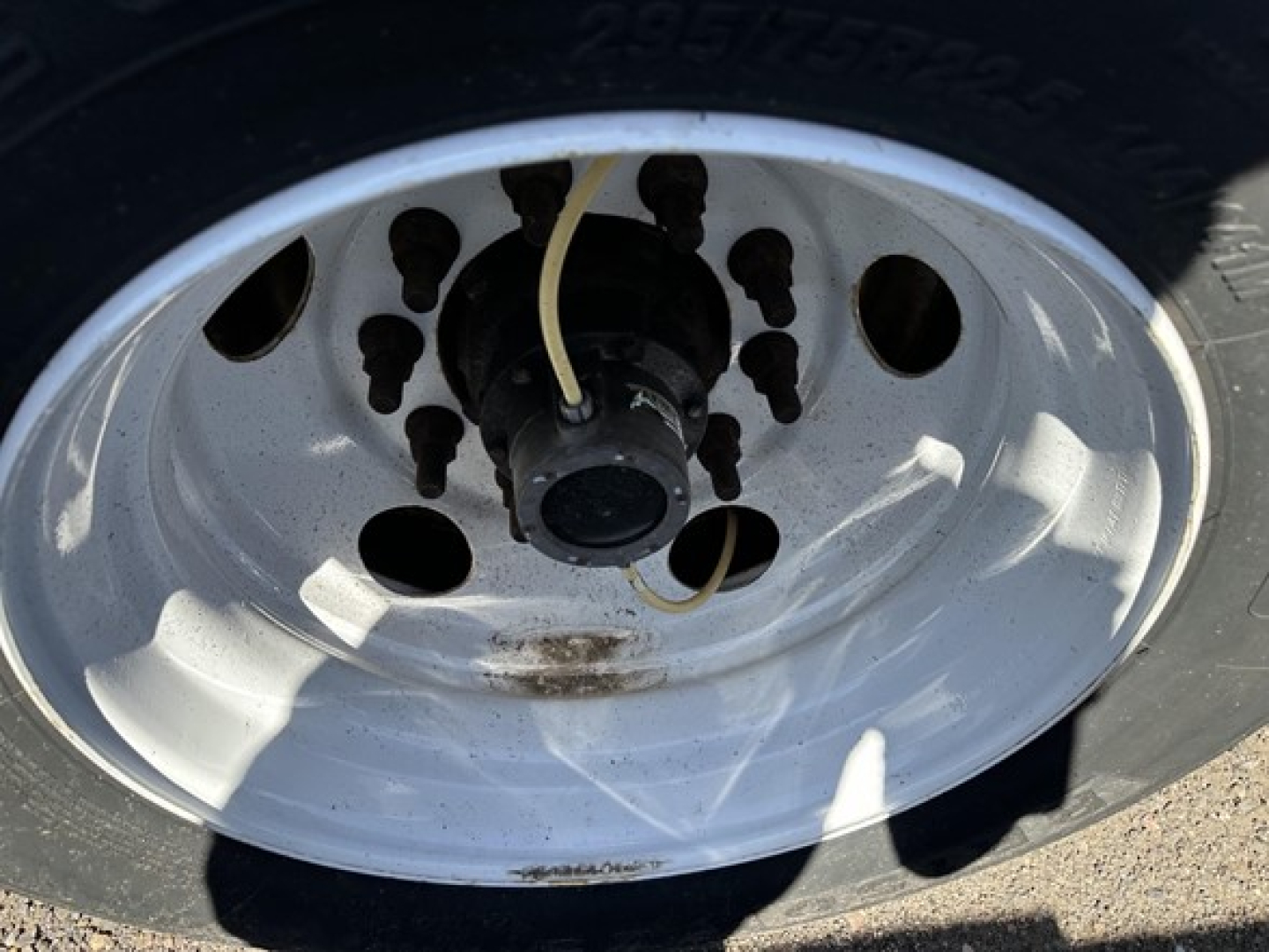 Wheel of a Fontaine trailer showing a white steel rim with lug nuts and a hub, with a tan flexible line coiled near the center.