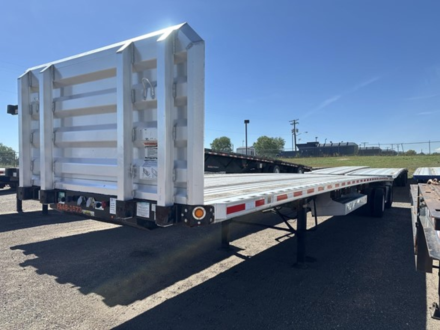Trailer flatbed showing rear ramp and white hydraulic air-ride? spread-axle Fontaine 48' combo with tall end gate and undercarriage.