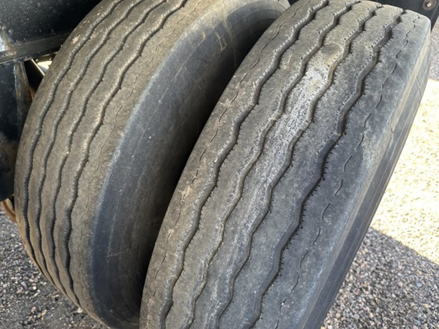 Trailer wheel pair with treaded tires on Fontaine 48' spread air combo flatbed showing worn tread and sidewalls.