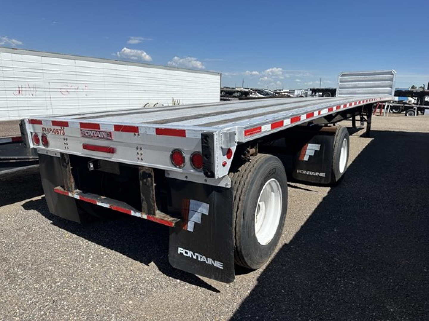Fontaine 48' spread air-ride flatbed trailer with dual rear axles, aluminum deck, red and white reflective tape, rear lights and mud flaps labeled Fontaine.
