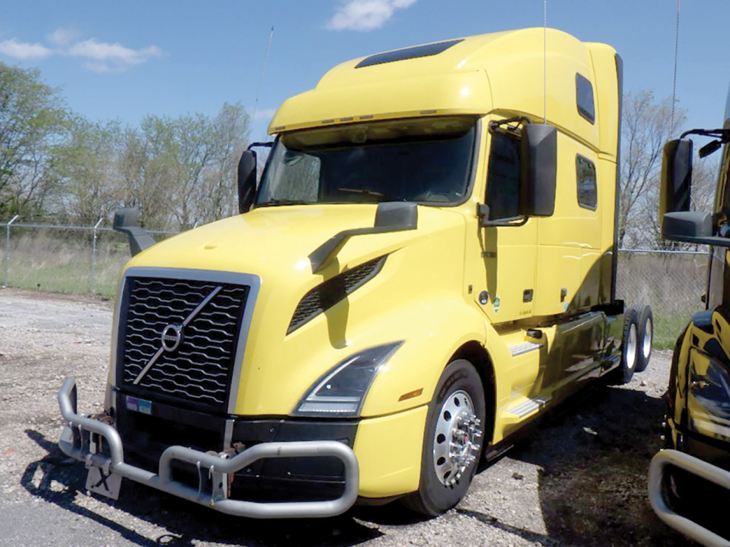 Yellow Volvo VNL 860 tractor-trailer in-service with front bumper guard and large grille; sleeper cab, side mirror, and wheel well visible.