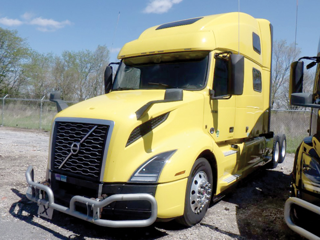 Yellow Volvo VNL 860 tractor-trailer in-service with front bumper guard and large grille; sleeper cab, side mirror, and wheel well visible.