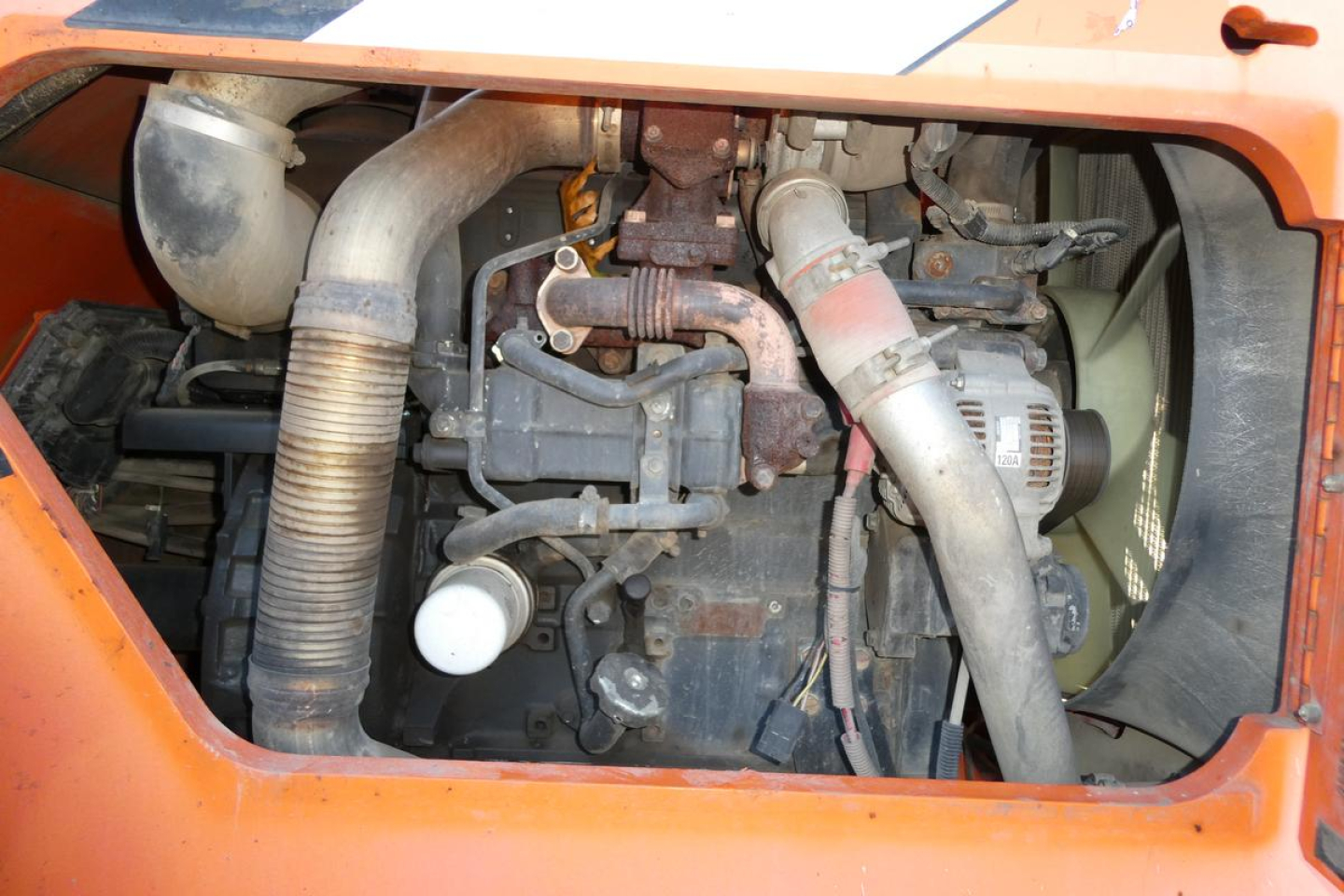 JLG 8042 engine bay showing exhaust manifold, hoses, radiator, alternator, and air intake duct in orange equipment housing.