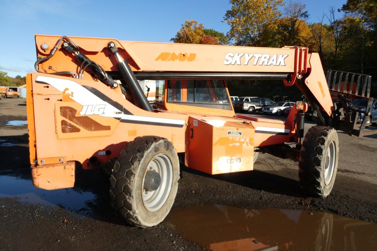 JLG SkyTrak 8042 telescopic boom lift in orange, side view showing oversized tires and lift arm with hydraulic cylinders.