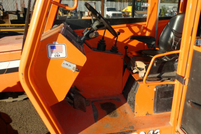 Operator cabin of an orange JLG 8042 telescopic lift showing dashboard, steering column, and control pedals.