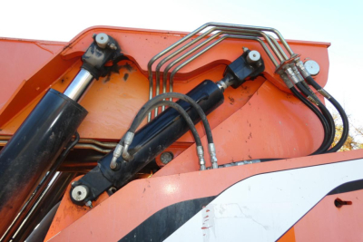 Hydraulic cylinders and hoses on a JLG 8042 telescopic lift boom section showing hydraulic lines and bracket hardware.