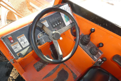 Operator cabin of a JLG 8042 telescopic lift showing steering wheel, control levers, and dashboard.