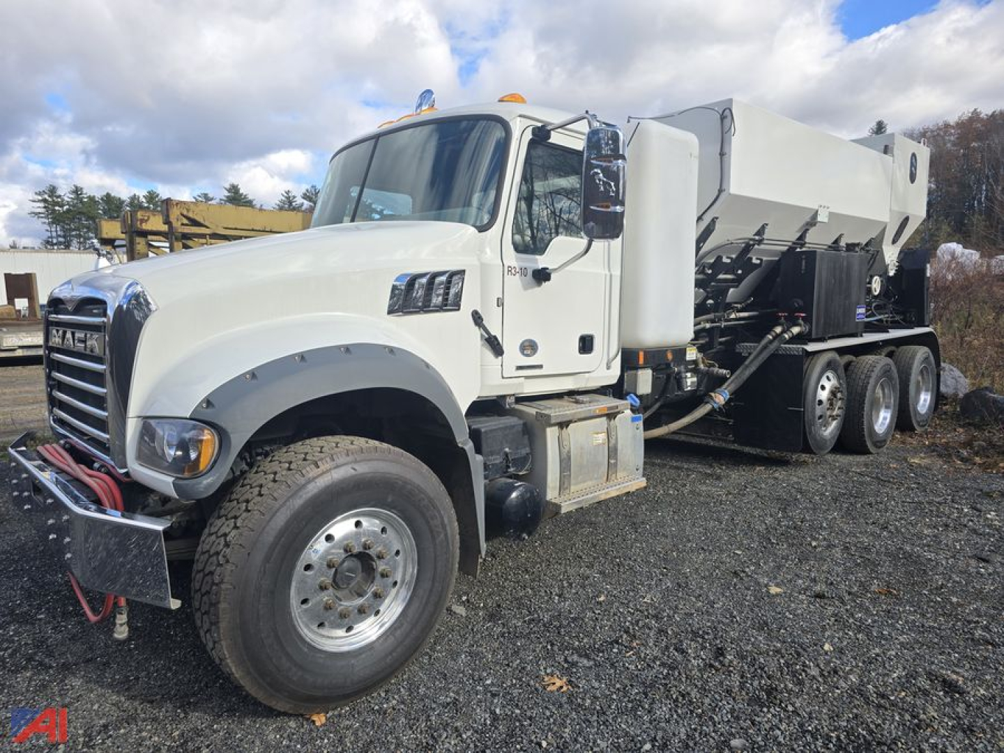 Truck cab and volumetric concrete mixer body on a white Mack Granite GR64F, side view showing chassis and wheels, gray mixer drum, front bumper with winch lines.