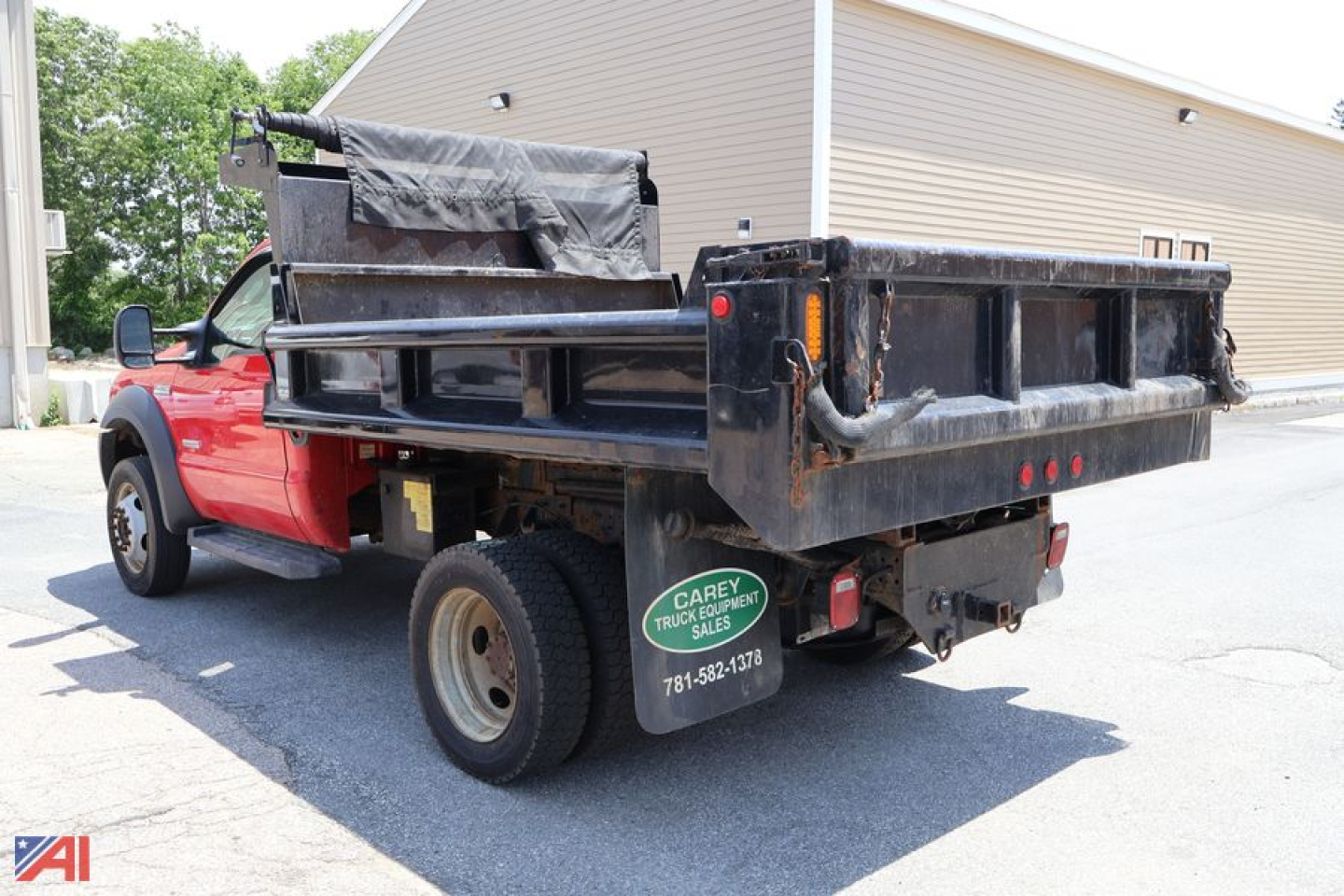 Ford F-450 dump truck with black dumping bed and plow equipment, red cab, rear view showing泥undefined tailgate area and green spare tire cover