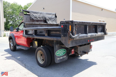 Ford F-450 dump truck with black dumping bed and plow equipment, red cab, rear view showing泥undefined tailgate area and green spare tire cover