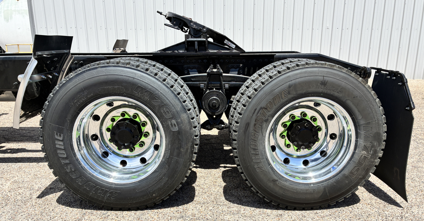 Mack GR64FT truck tandem rear wheels showing second axle and dual tires with chrome rims and green lug nuts.