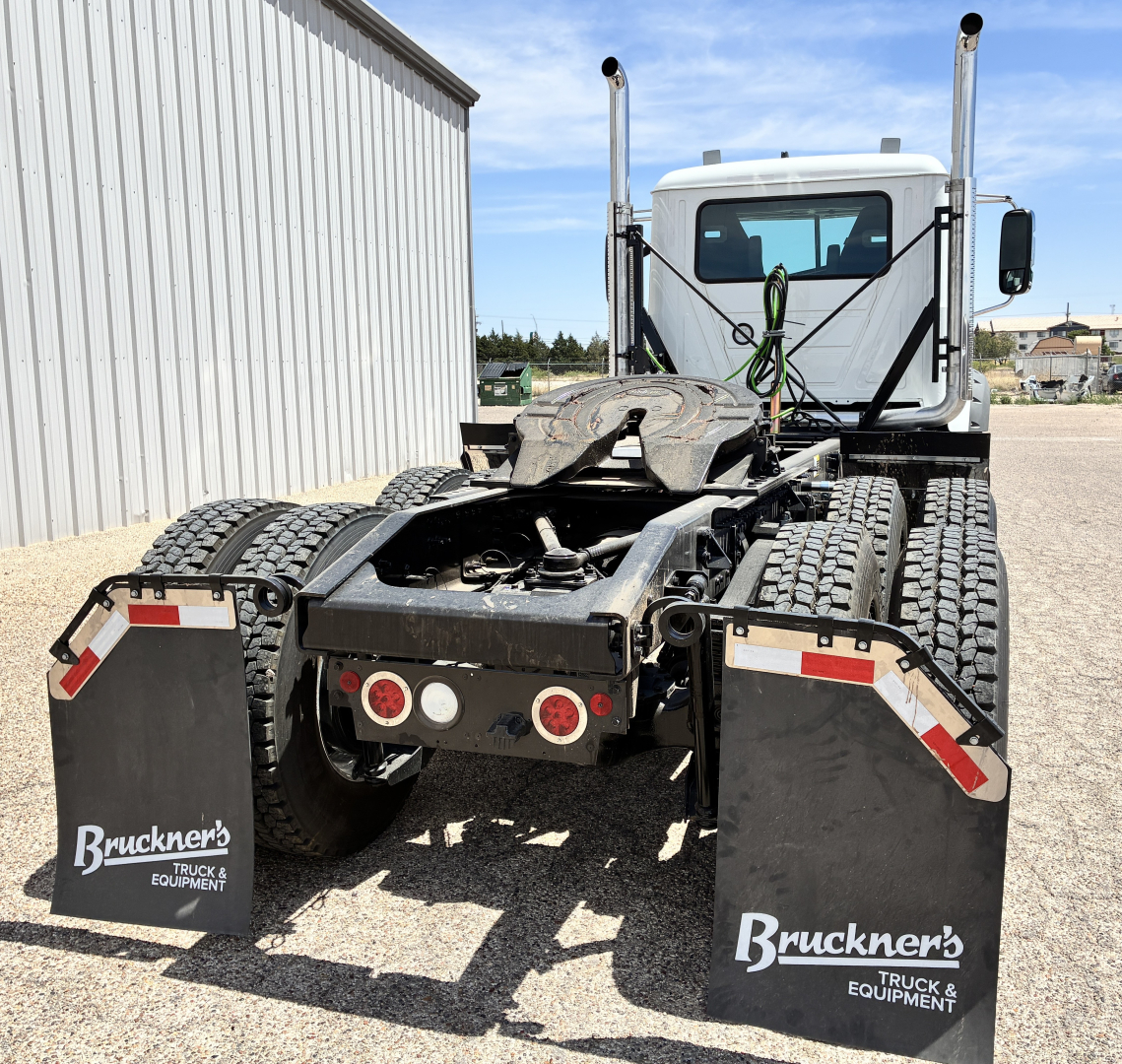 Truck chassis and cab rear view of a 2027 Mack GR64FT tractor showing dual rear fenders, five-wheel coupling, and mud flaps with Brunkner's Truck & Equipment branding.