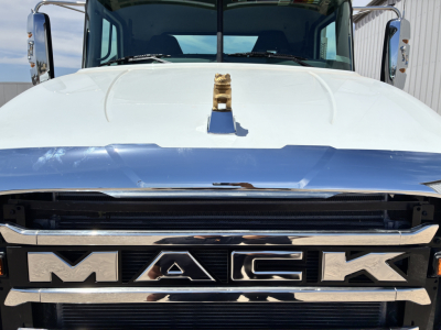 Front of white 2027 Mack GR64FT truck showing MAC K grille letters and chrome bumper; hood ornament centered on hood.