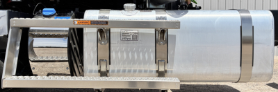 Truck fuel tank and side step of a 2027 Mack GR64FT conventional daycab showing aluminum cylindrical tank with protective side step and mounting brackets.