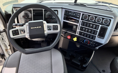 Mack GR64FT truck cabin dash and steering wheel showing gauges and control panels.