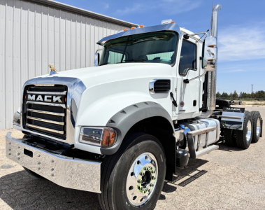 Mack GR64FT conventional daycab truck with white cab, chrome bumper, and dual rear axles. Visible components include large front grille, Mack emblem, side mirrors, exhaust stack, and fuel tanks.