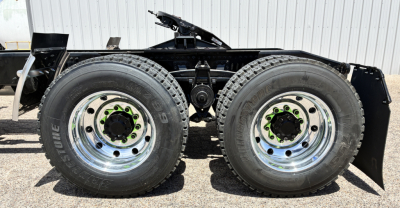 Mack GR64FT truck tandem rear wheels showing second axle and dual tires with chrome rims and green lug nuts.