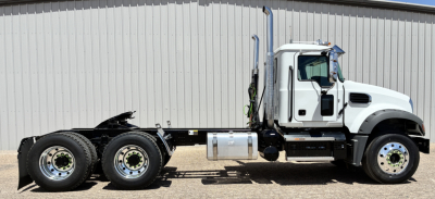 Mack GR64FT conventional daycab truck side view showing sleeper cab, white paint, dual rear axles with fuel tank, exhaust stack, and chassis.