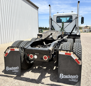 Truck chassis and cab rear view of a 2027 Mack GR64FT tractor showing dual rear fenders, five-wheel coupling, and mud flaps with Brunkner's Truck & Equipment branding.
