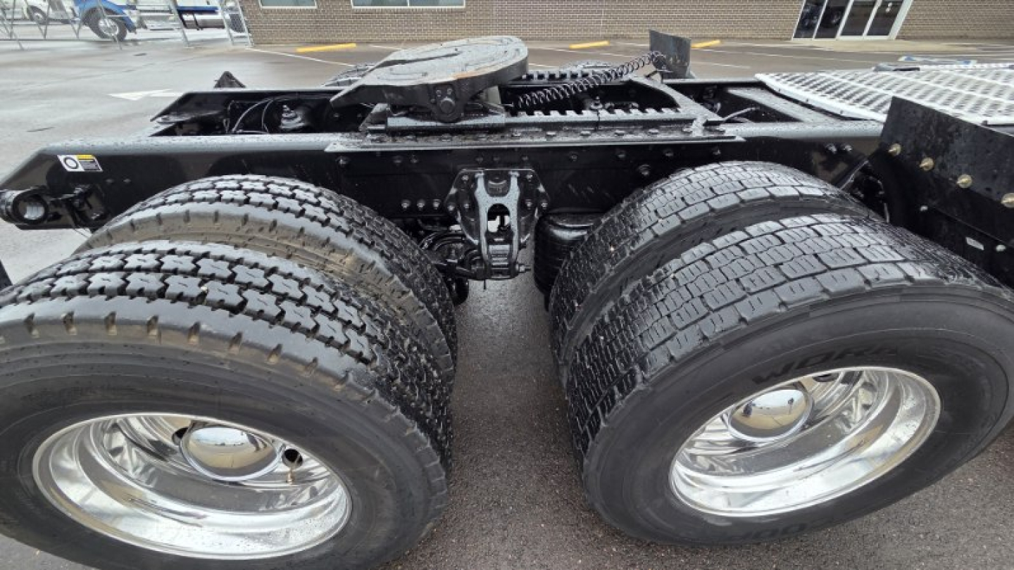 Kenworth T880 chassis view showing dual rear axles and fresh tires, rear frame with components.