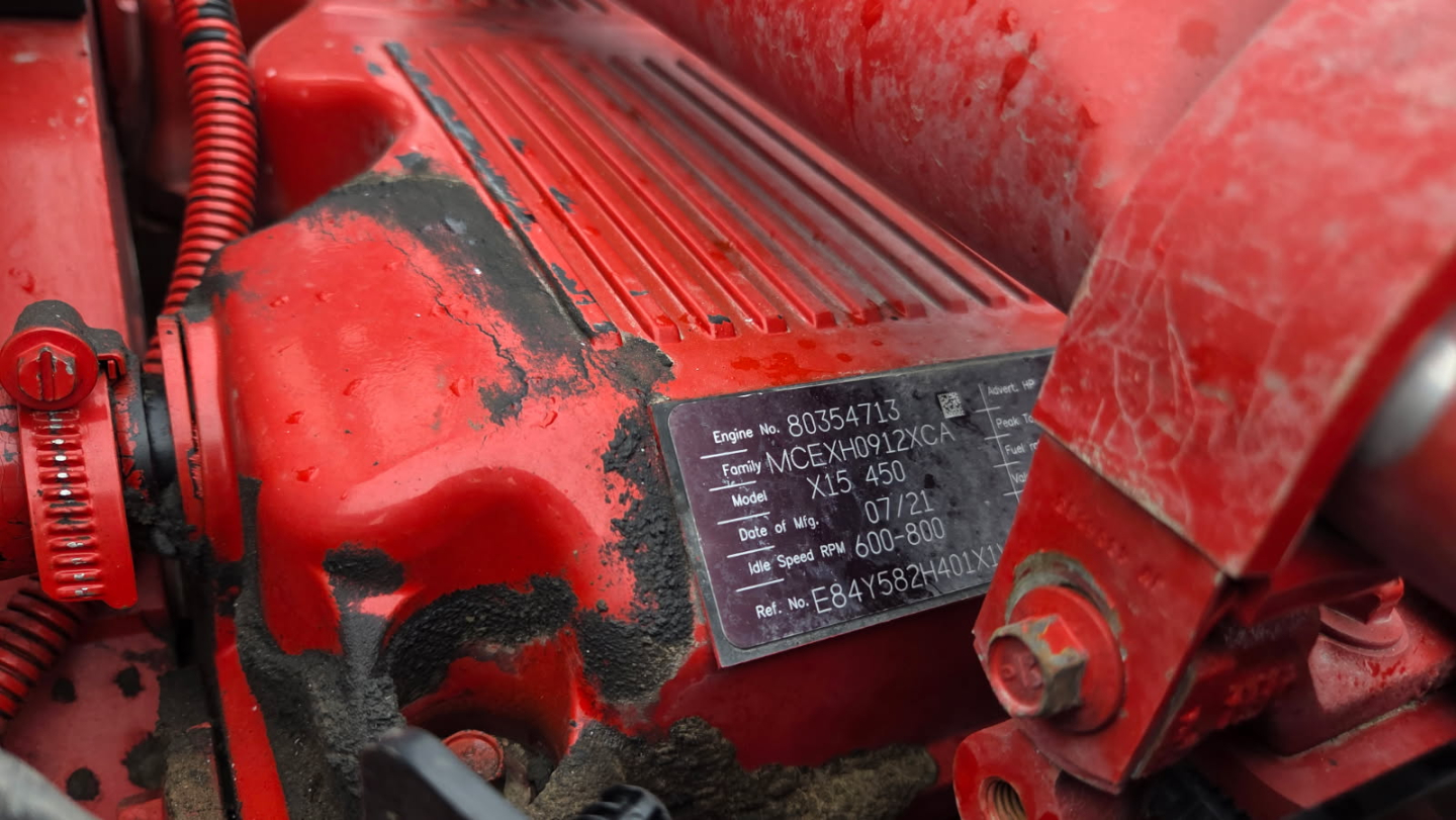 Kenworth T880 engine bay area with red exterior showing identification plate with model and serial details.