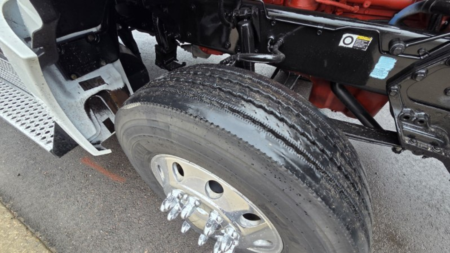 Kenworth T880 front axle and wheel showing dual tires and suspension components.