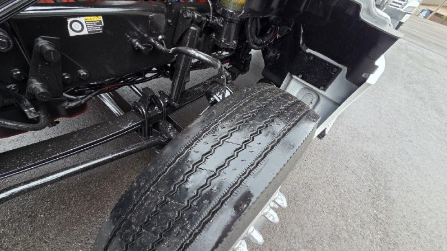 Front left wheel and suspension area of a 2022 Kenworth T880 with visible tire tread and chassis components
